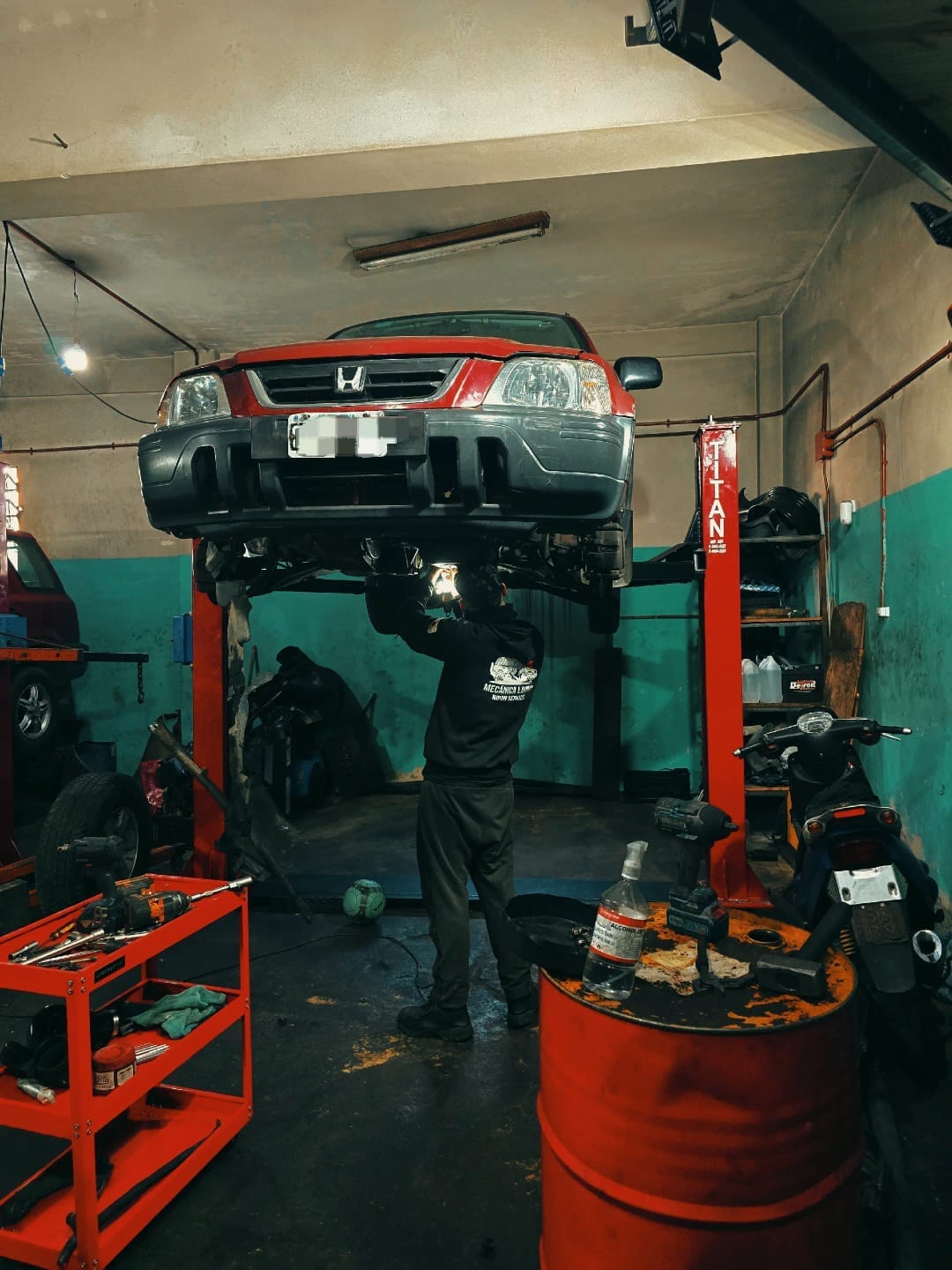 Honda elevada con Martín trabajando debajo en el taller